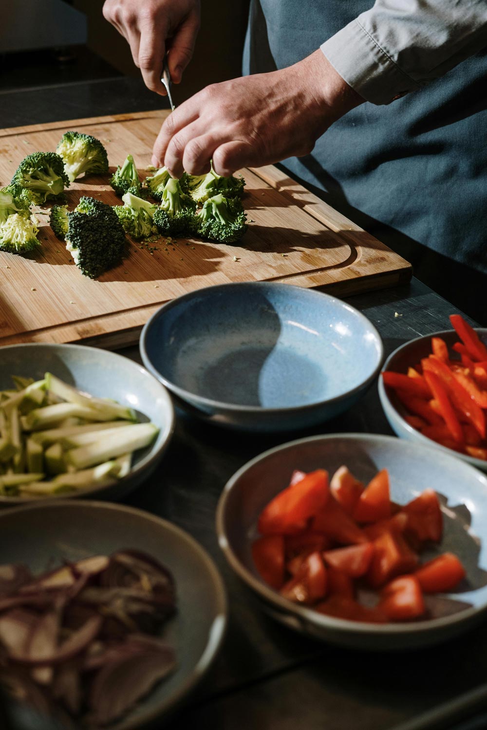 A man's hands cutting broccoli on a cutting board