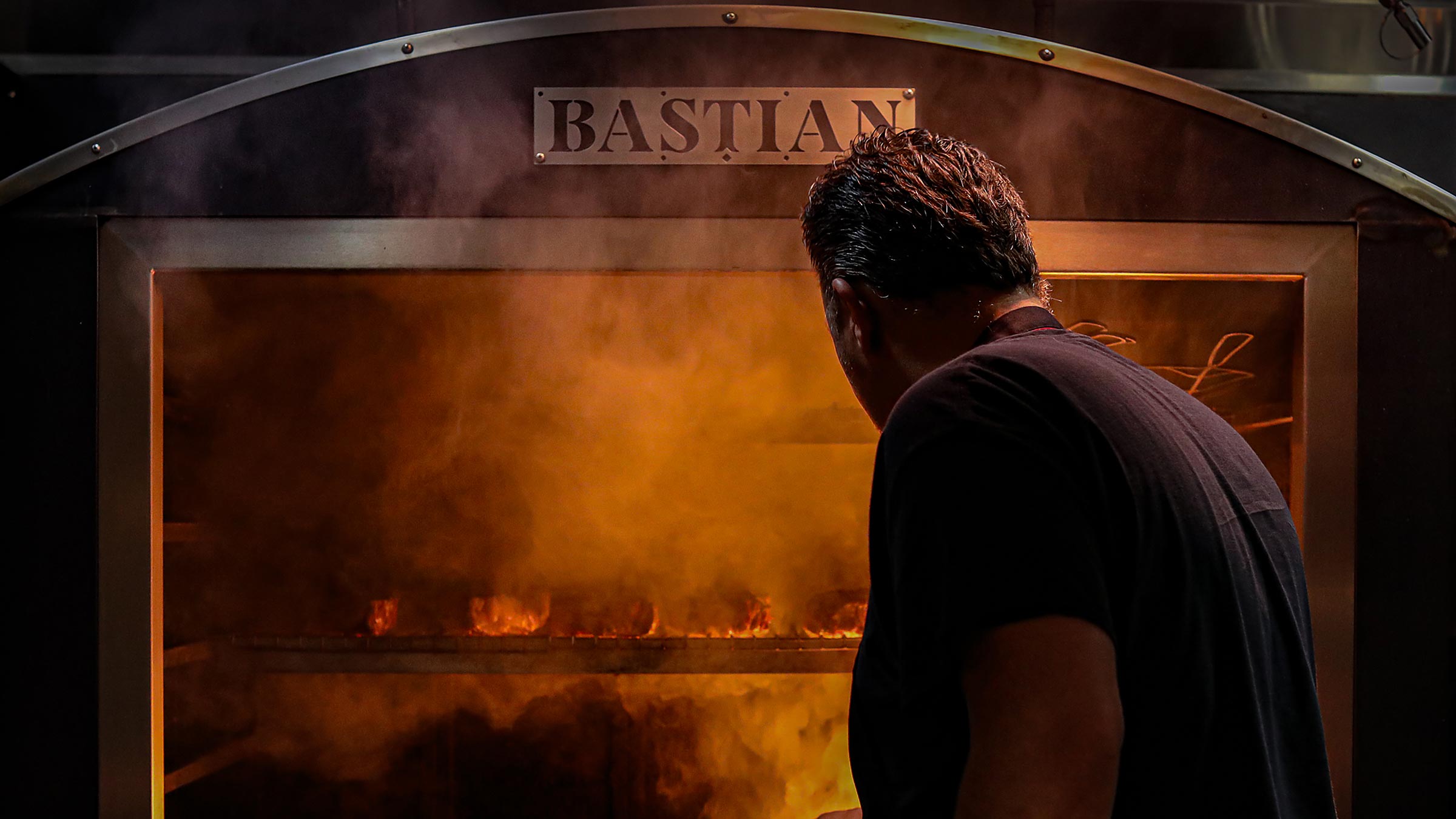 Chef Doug Tsaltis standing in front of large oven