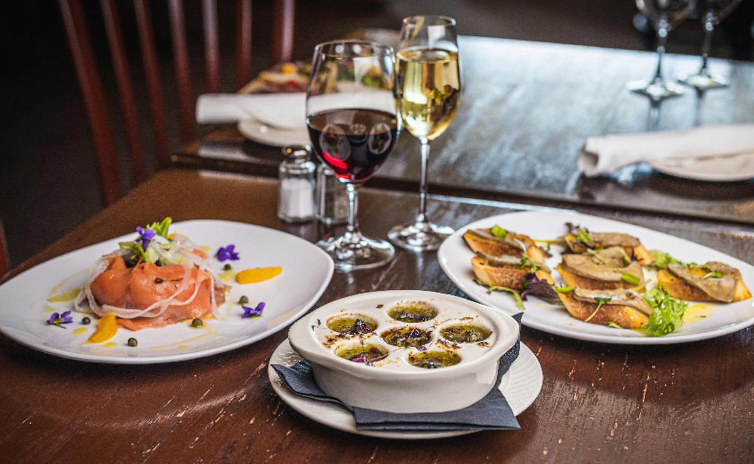 Dinner table at Le Voltaire Restaurant with plates of food and glasses of wine